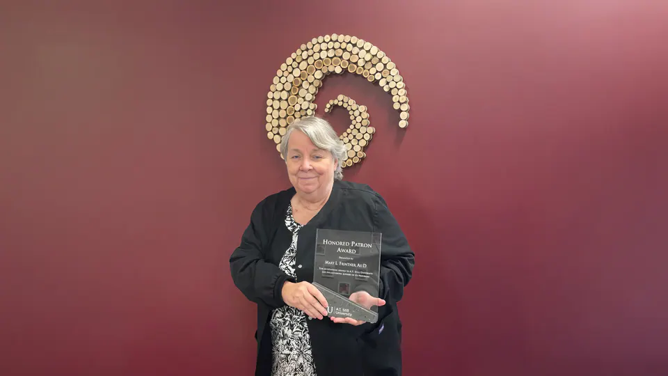 Dr. Mary Frintner holding her Honored Patron Award from A.T. Still University