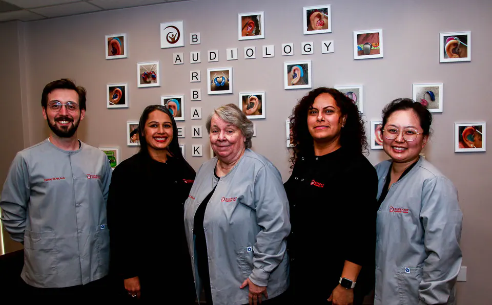 The Audiology Center of Burbank team standing together in front of the office’s “Burbank Audiology” letter wall