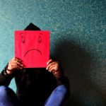 man holding up a sad face
